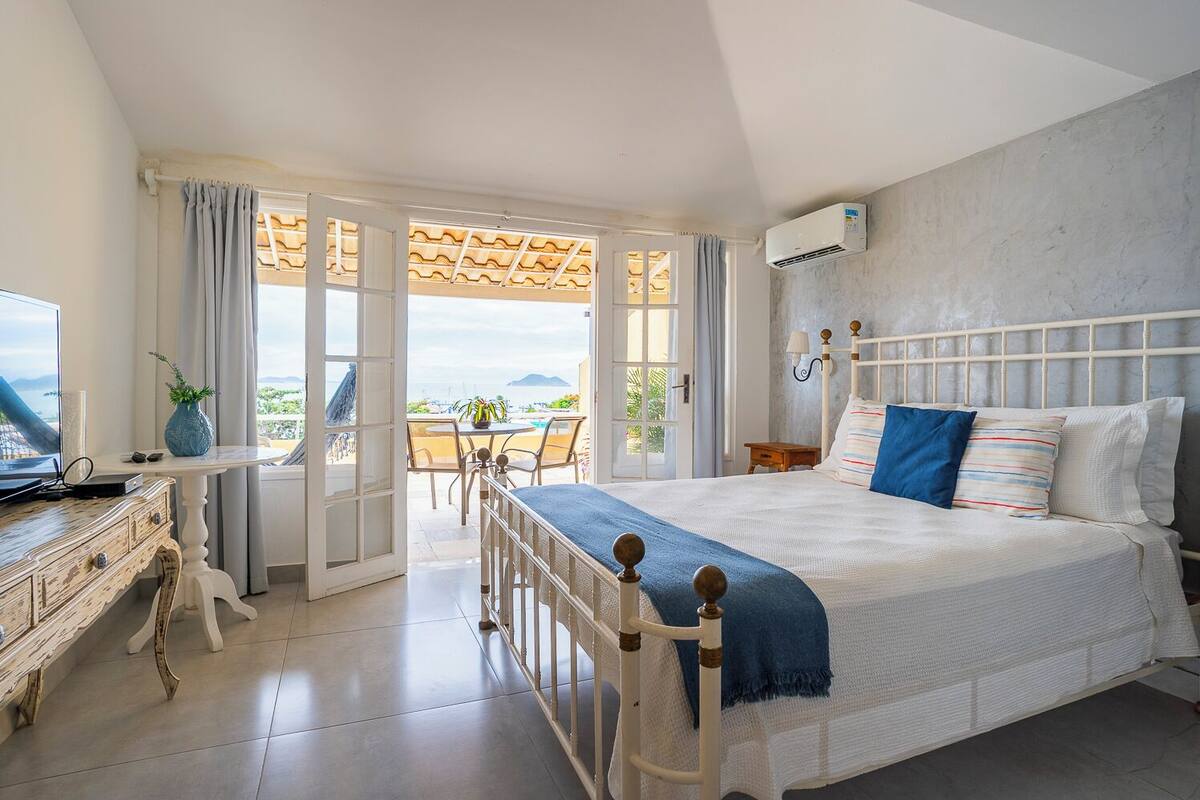 A bedroom with a bed, a desk, and a view of the outdoors.