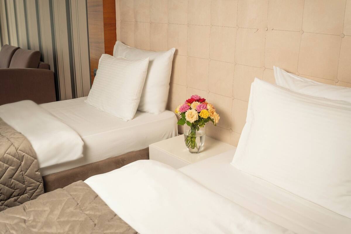 Habitación de hotel con dos camas, un jarrón de flores y una cortina a rayas.