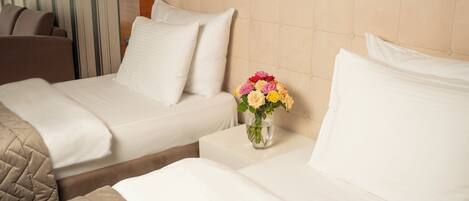 Habitación de hotel con dos camas, un jarrón de flores y una cortina a rayas.