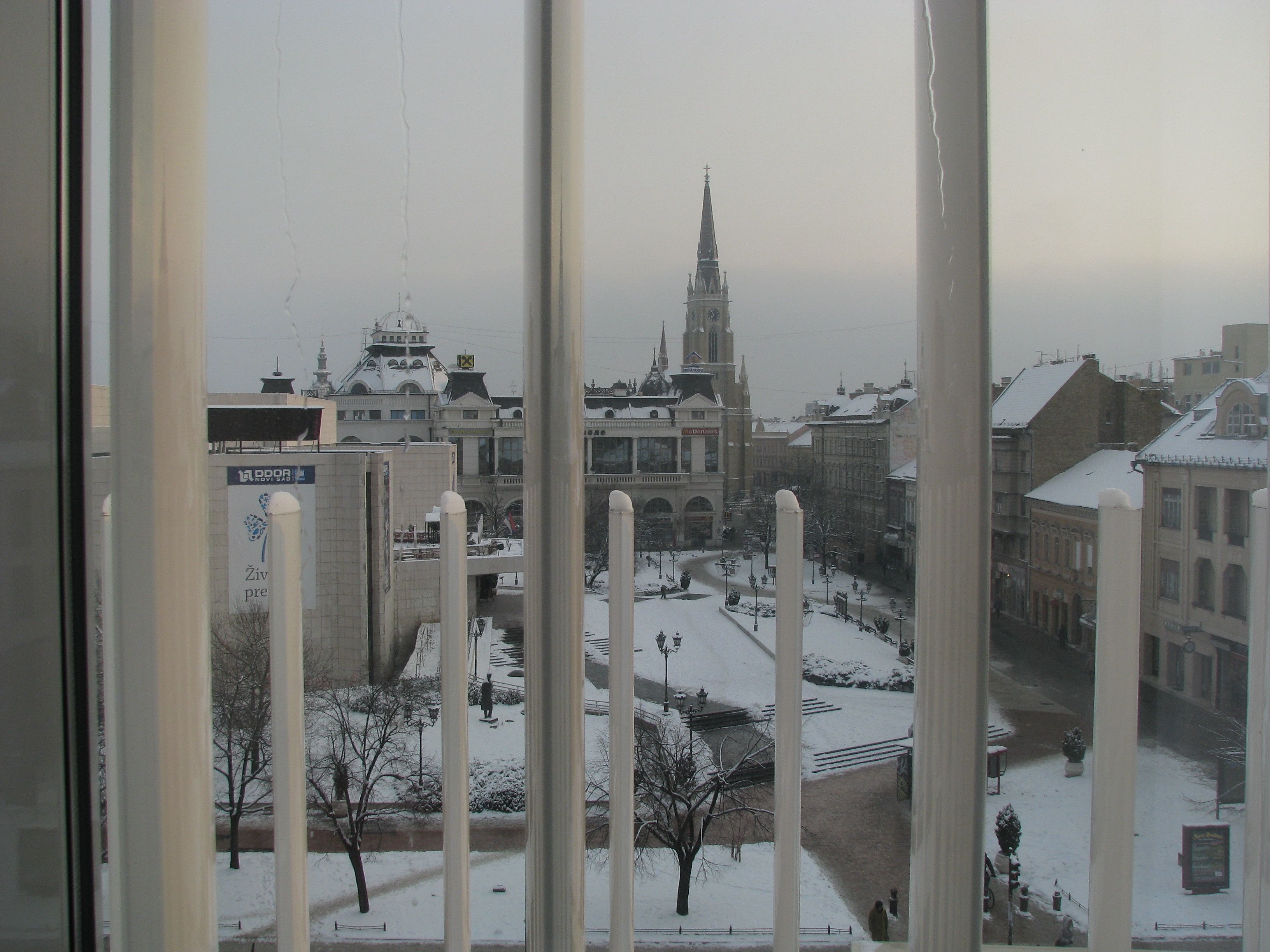A view of a cityscape with snow-covered streets and buildings, including a prominent church tower.
