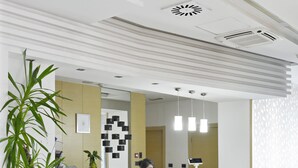 A reception area with a modern design, including a reception desk, a clock, and a large potted plant. - Garni Hotel Centar (Novi Sad)