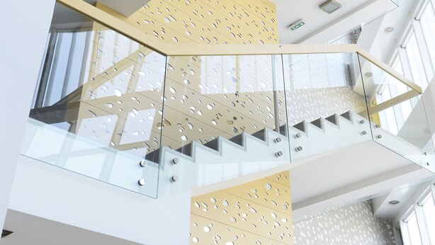 A multi-level interior with glass railings and a geometric patterned wall. - Garni Hotel Centar (Novi Sad)
