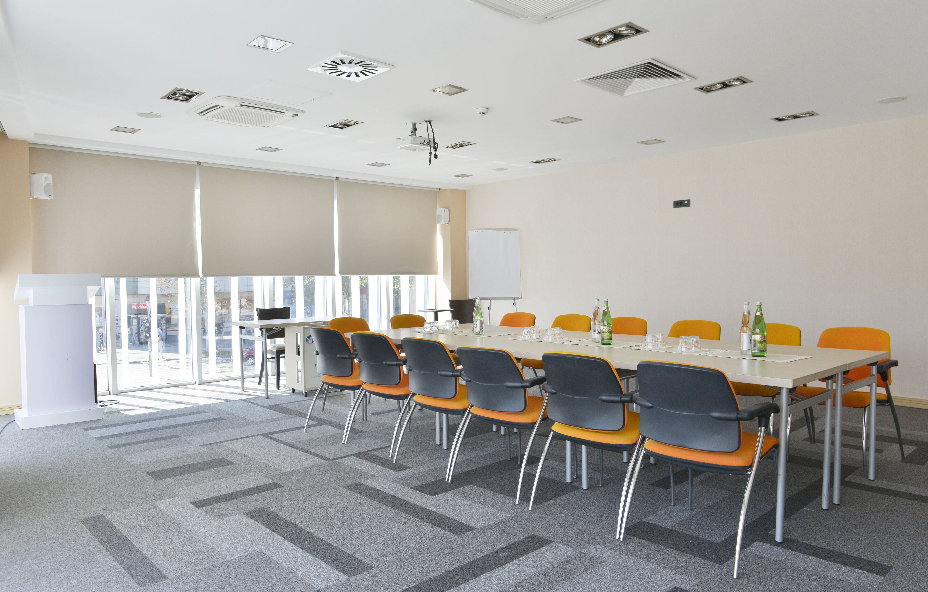 A conference room with a long table, orange chairs, and a whiteboard.
