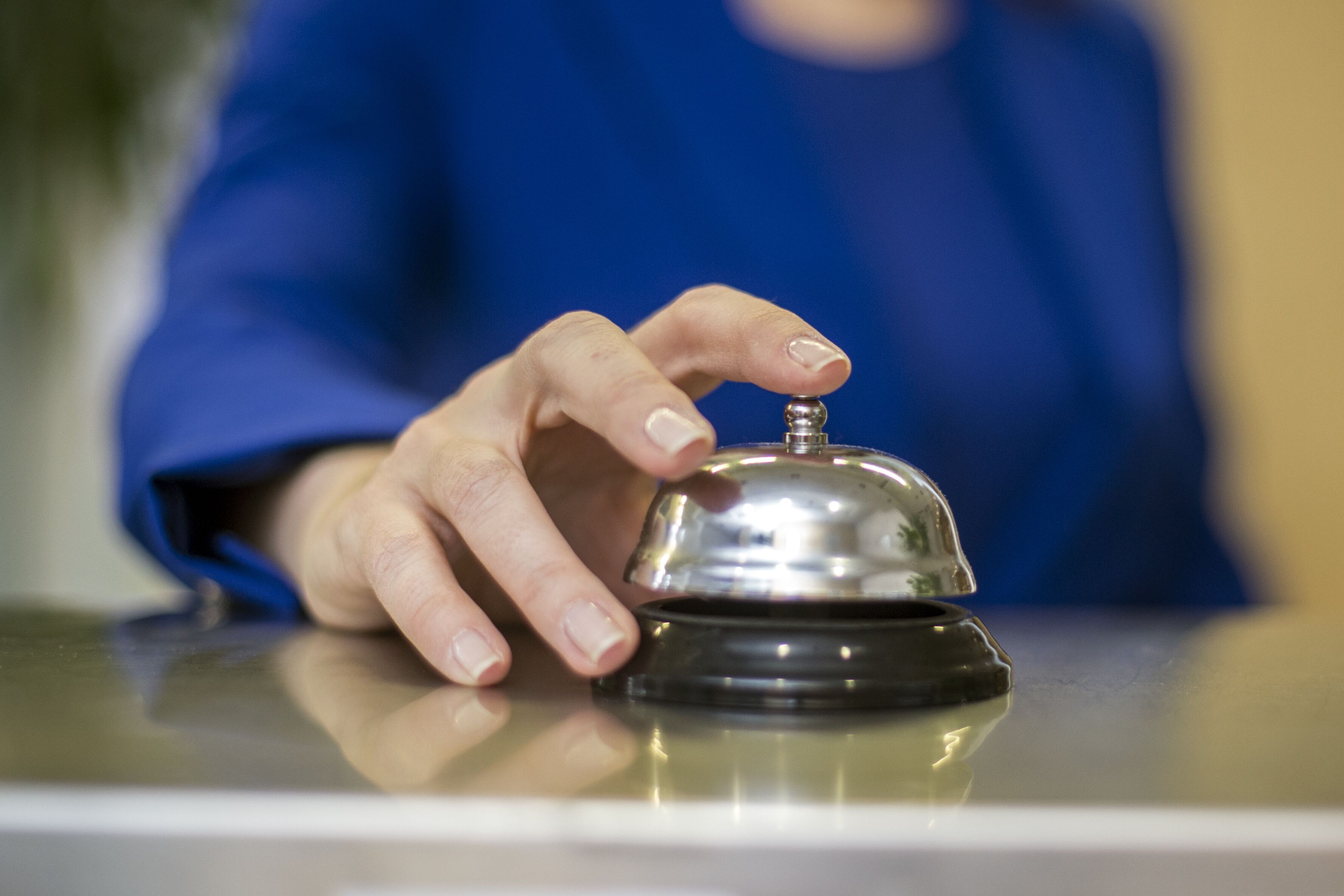 A hand pressing a hotel room's bell.