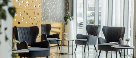 A modern lobby with two black armchairs, a small table, and a potted plant.