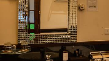 A bathroom with a round sink, a mirror with mosaic tiles, and a towel rack.