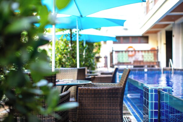 An outdoor pool area with wicker furniture and a blue umbrella.