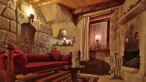 Una habitación acogedora con un sofá rojo, una mesa de madera y una pared de piedra con detalles tallados.