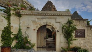 Un edificio de piedra con puerta de madera, una escalera y un letrero que dice