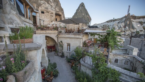 Un patio con muros de piedra, plantas en macetas y zonas de estar al aire libre.