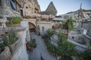 A courtyard with stone walls, potted plants, and outdoor seating areas. - Koza Cave Hotel (Nevsehir)