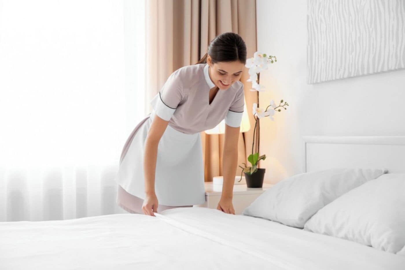 Una cama bien tendida con sábanas blancas en una habitación de hotel.