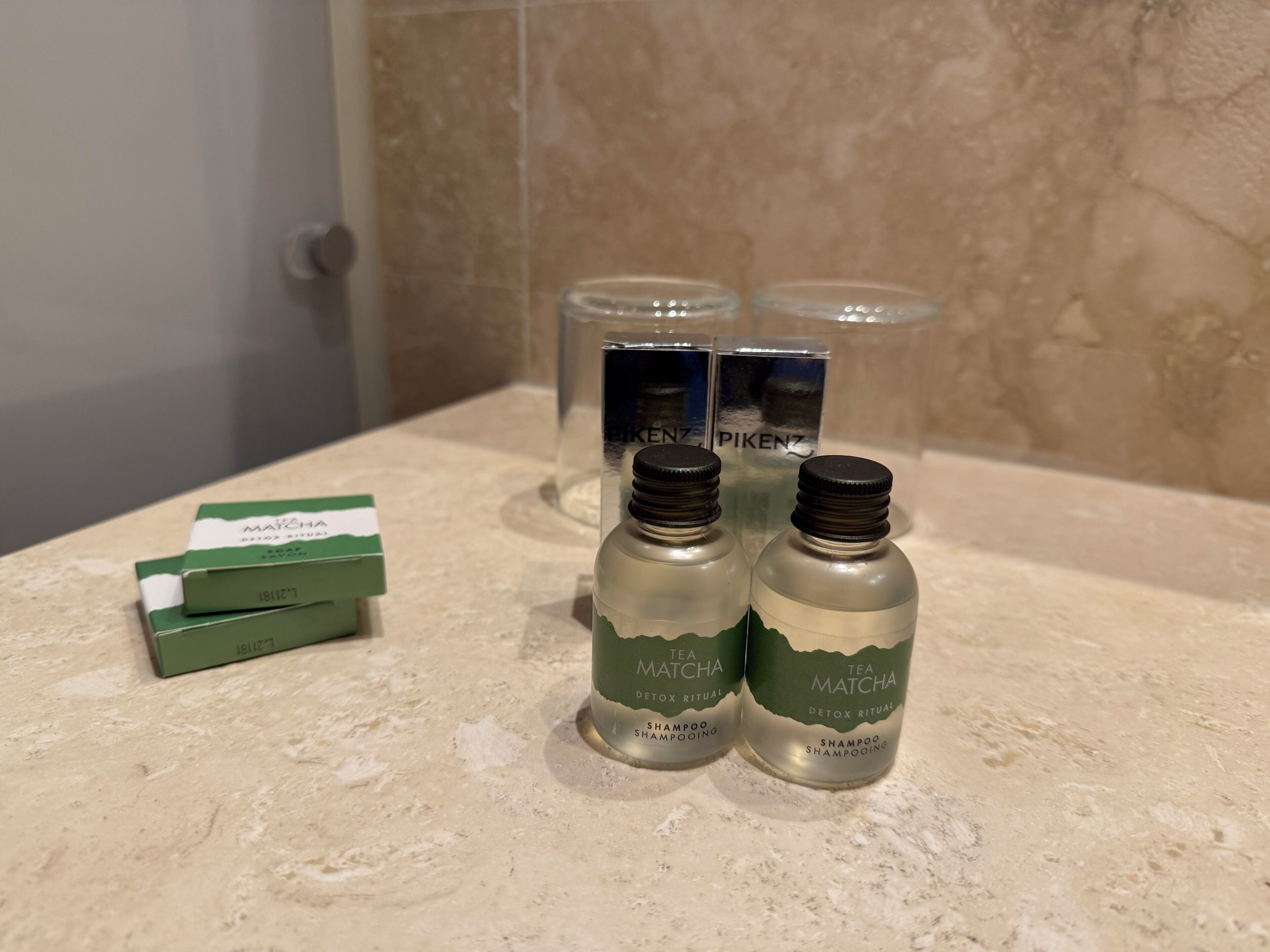 Un meuble-vasque de salle de bain avec deux bouteilles de shampoing détoxifiant « Tea Matcha Detox Ritual » et une boîte de savon détoxifiant « Matcha Detox Ritual ».