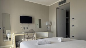 Une chambre d’hôtel avec un grand lit, un bureau avec une chaise, une télévision et une armoire.