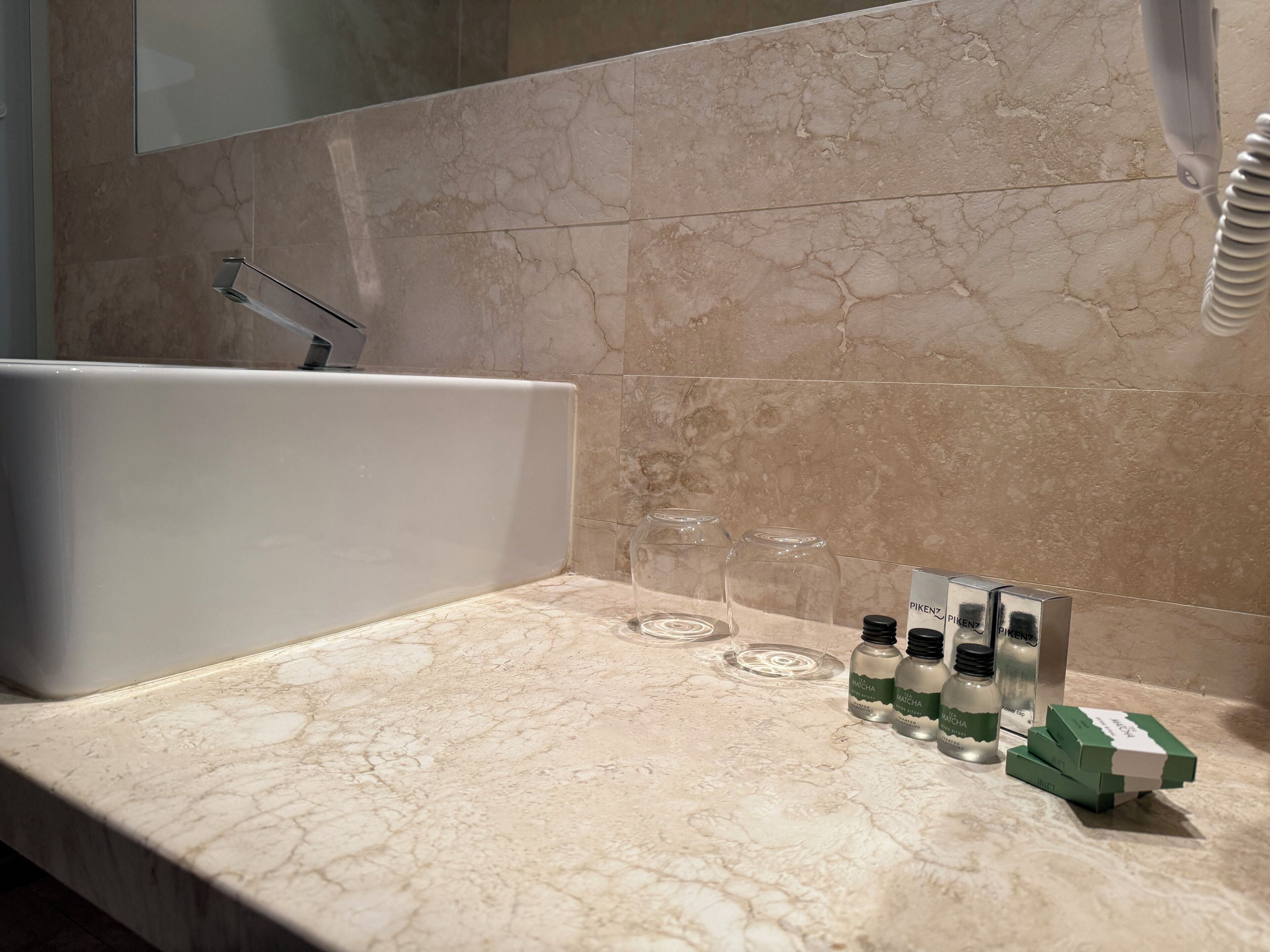 A bathroom with a bathtub, a mirror, and a countertop with bottles and a box.