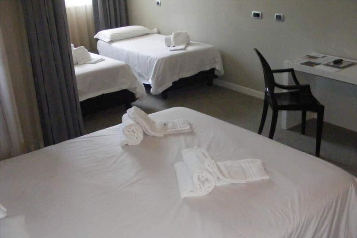 Ein Hotelzimmer mit zwei Betten, einem Schreibtisch und einem Stuhl.
