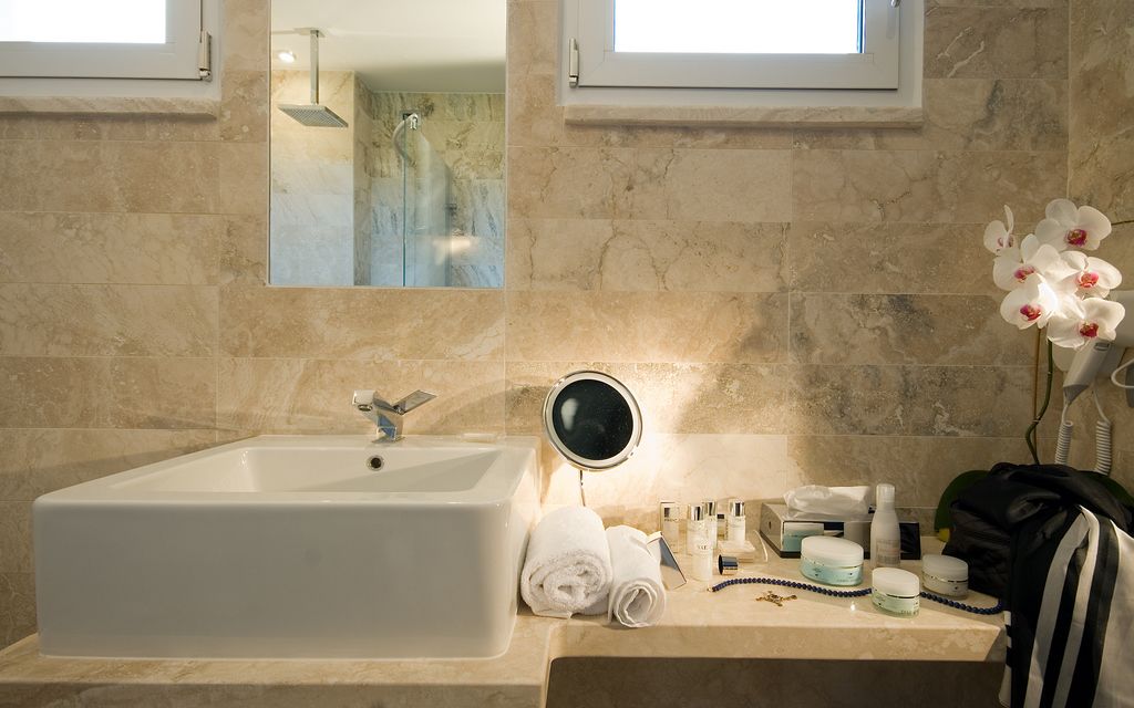 A bathroom with a large sink, a mirror, and a towel rack.