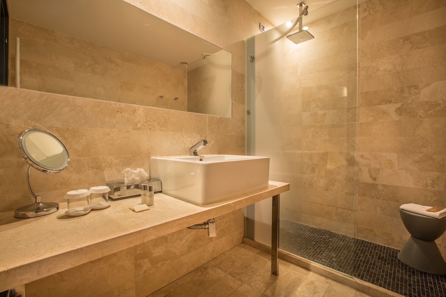 A modern bathroom with a large sink, a mirror, a shower, and a toilet.