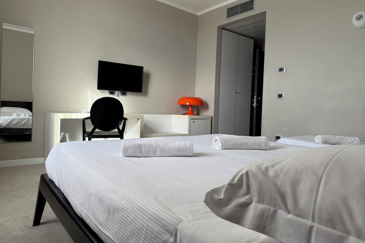 Ein Hotelzimmer mit einem großen Bett, einem Schreibtisch, einem Stuhl, einem Fernseher und einem Kleiderschrank.