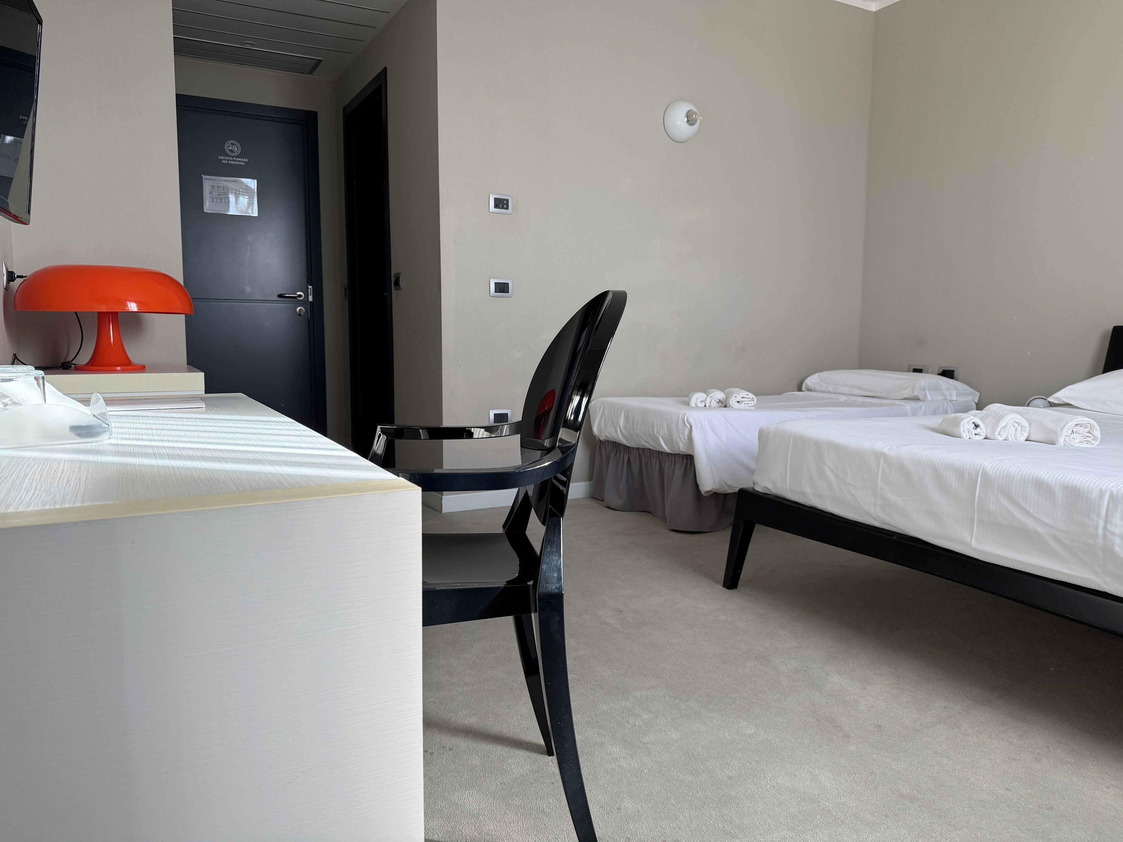 Una habitación de hotel con escritorio, silla, dos camas y una puerta.