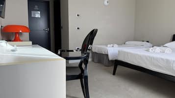 Una habitación de hotel con escritorio, silla, dos camas y una puerta.