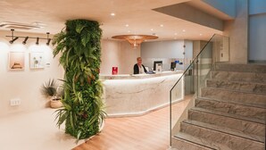 A modern reception area with a large vertical garden, a marble reception desk, and a staircase leading to upper floors. - Hotel Aloe Canteras (Las Palmas de Gran Canaria)