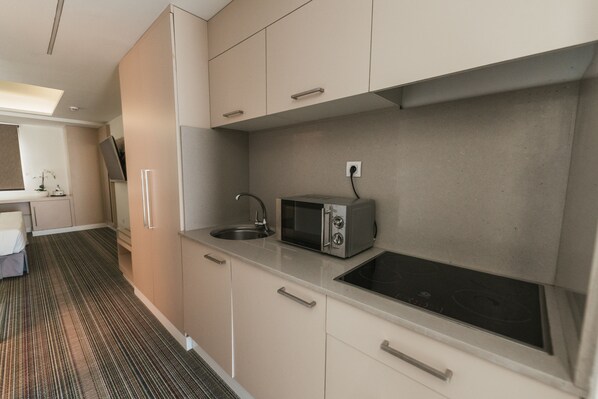 Una kitchenette compacta con microondas, pileta y electrodomésticos de acero inoxidable.