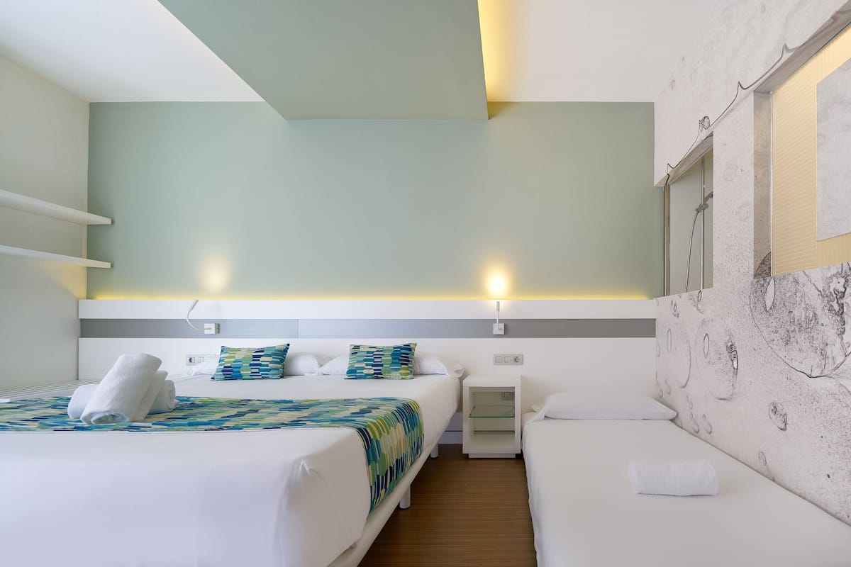 A hotel room with two beds, a nightstand, and a wall-mounted artwork.