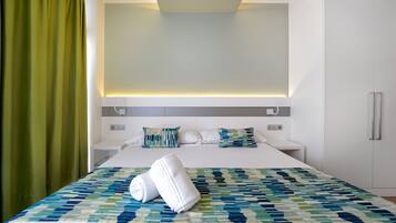 Ein modernes Hotelzimmer mit einem ordentlich bezogenen Bett, einem Nachttisch und einem großen Fenster mit Vorhängen.