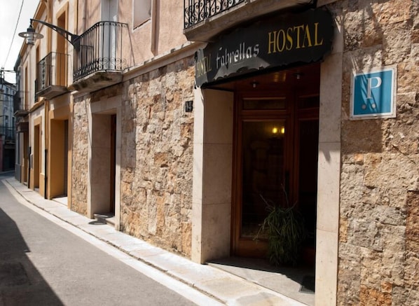 A stone building with a sign reading "Hostal Fabrellas".