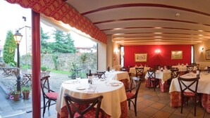 Un espace de restauration intérieur avec des tables et des chaises, des murs rouges et une vue sur l’extérieur.