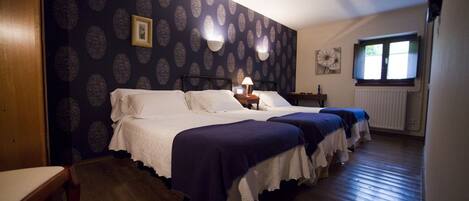 A hotel room with a large bed, two bedside tables, a window with blinds, and a patterned wallpaper.