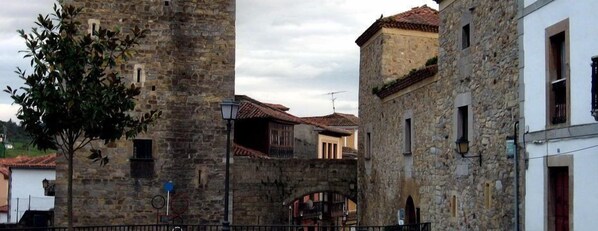 A stone building with a traditional architectural style, featuring a central archway and a small balcony. - Hotel Castillo de Valdés Salas (Salas)