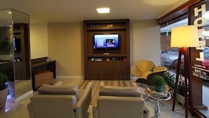 A hotel room with a TV, seating area, and a lamp. - Hotel Don Zepe (Florianópolis)