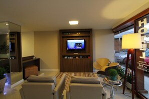 A hotel room with a TV, seating area, and a lamp. - Hotel Don Zepe (Florianópolis)