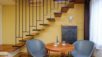 Un intérieur moderne avec un escalier, deux chaises, une table et une décoration représentant un crâne de taureau.