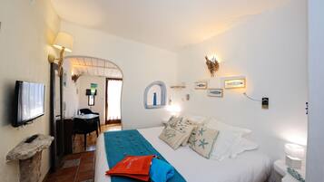 Una habitación de hotel con cama, escritorio, silla, televisión y baño.