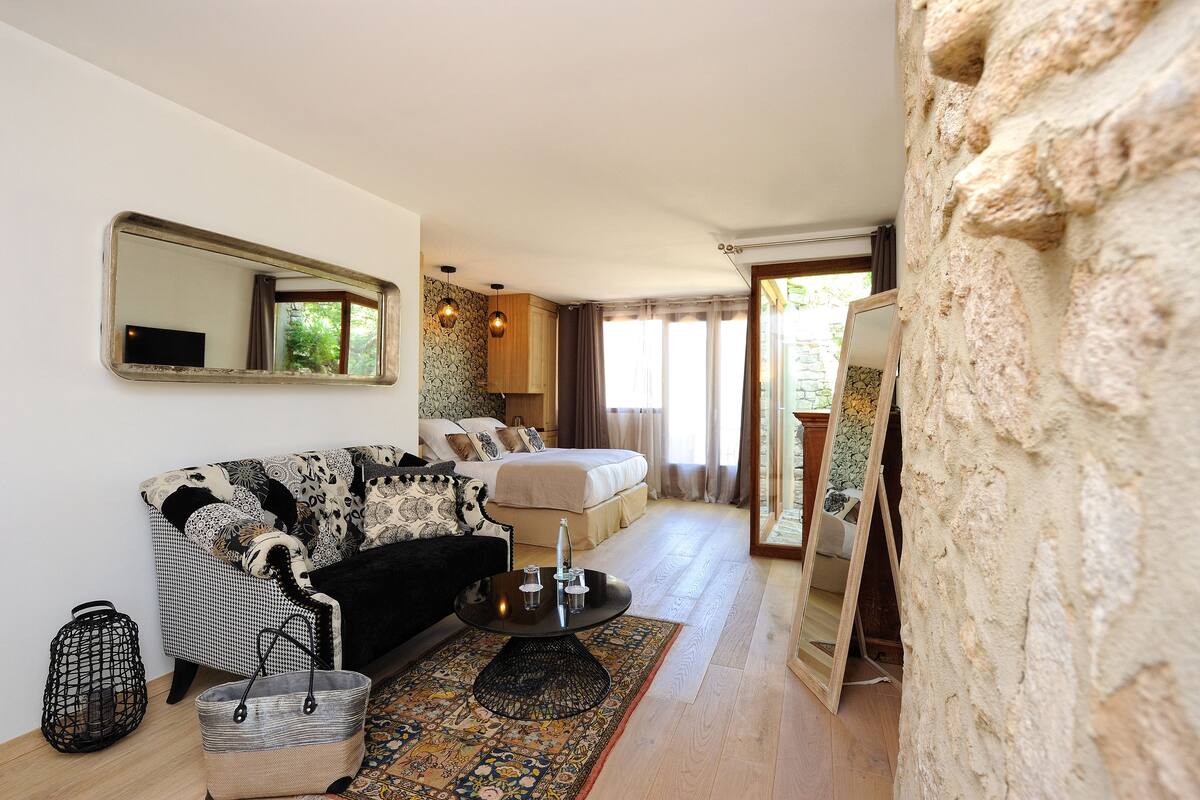 A cozy room with a sofa, a bed, a round table, and a mirror.