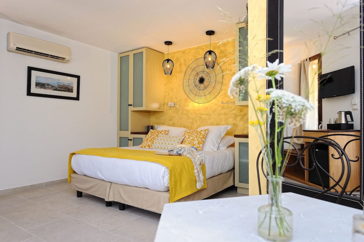 A bedroom with a bed, bedside table, and a vase with flowers.