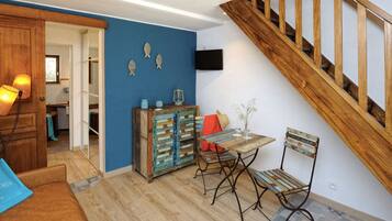 Een kamer met een houten trap, een tafel met stoelen, een kast en visdecoraties aan de muur.
