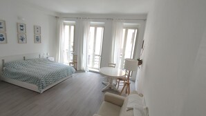 A spacious room with a bed, a dining table, and a sofa. - Casa Marina (Cagliari)