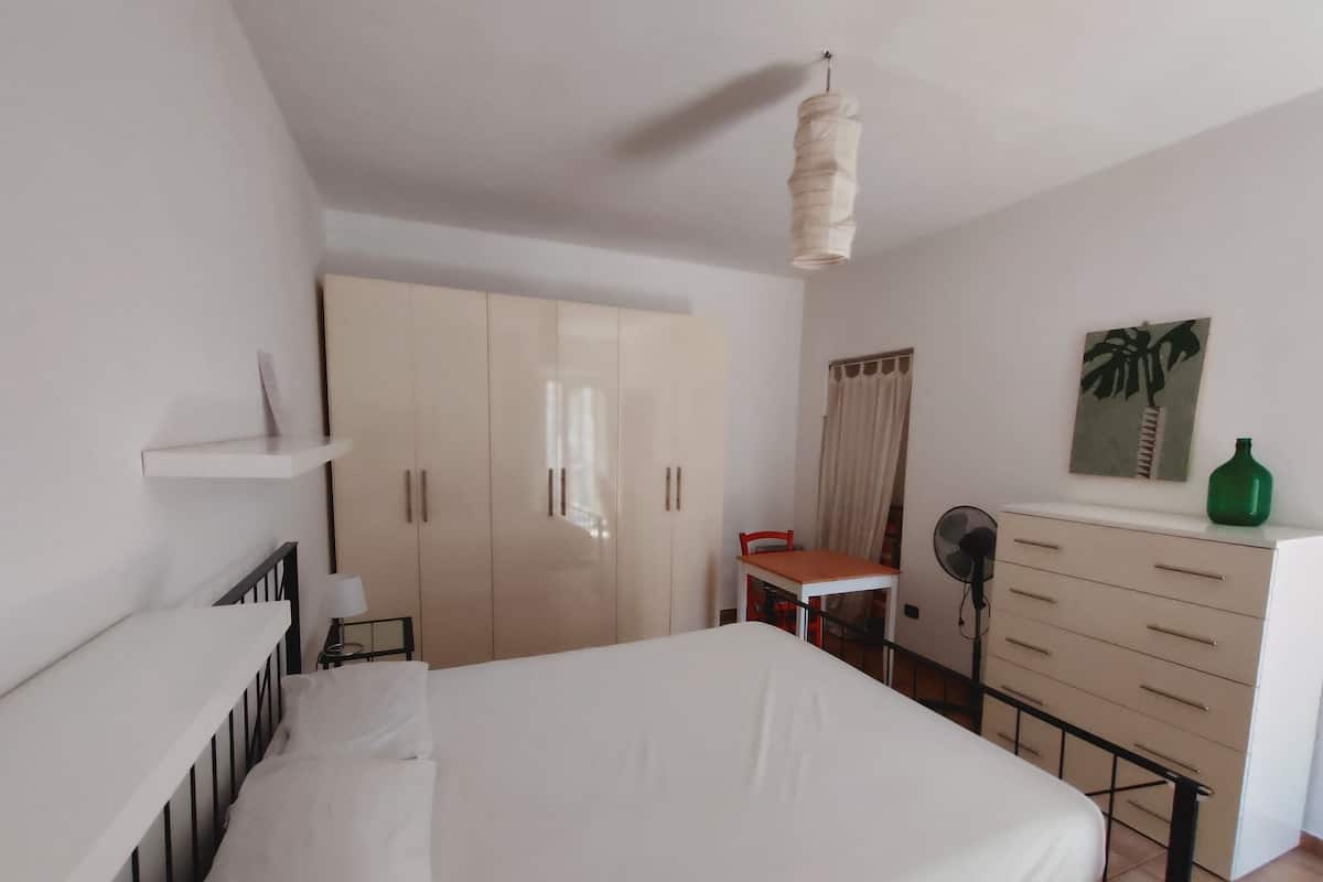 A bedroom with a bed, a wardrobe, a desk, and a chair.
