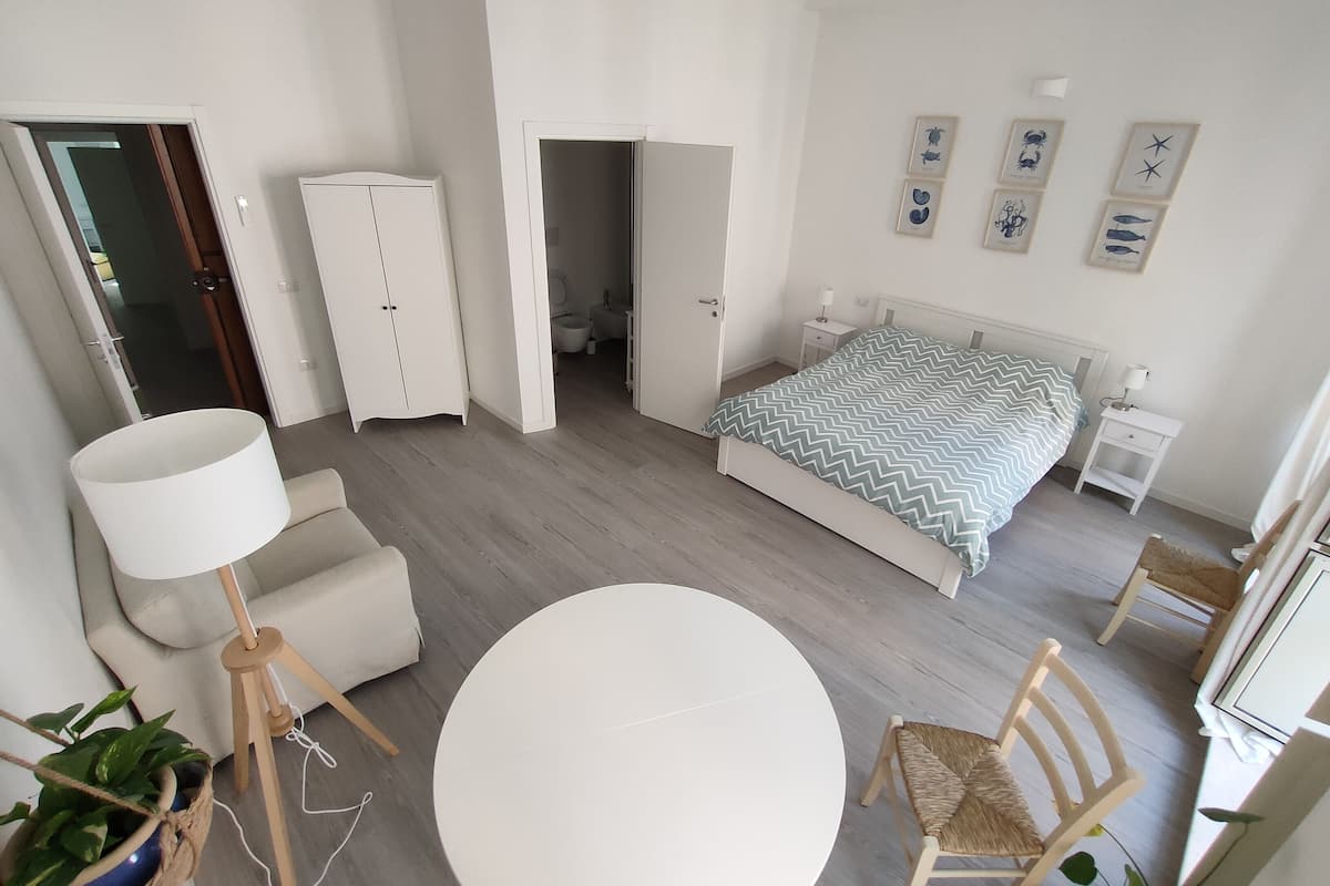 A modern bedroom with a bed, bedside tables, a chair, a round table, and a wardrobe.