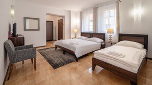 Ett hotellrum med två sängar, ett skrivbord, en stol, en TV och ett fönster med gardiner.