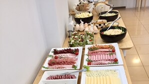 Ett buffébord med olika sorters mat, inklusive kött, ostar och sallader.