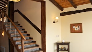 Una escalera con escalones y barandilla de madera que lleva a un rellano con una lámpara de pared y una pequeña mesa con un florero.
