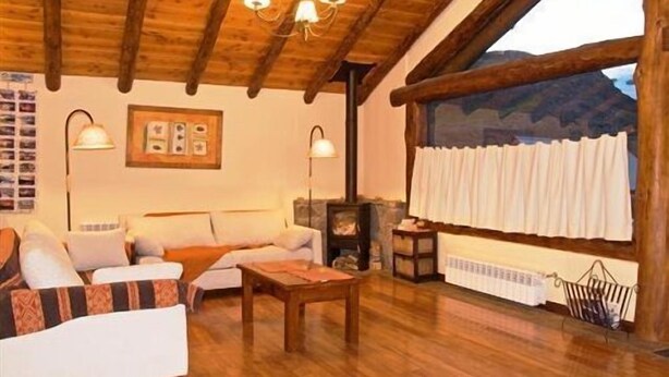 Una sala de estar acogedora con techo de madera, un sofá, una mesa y una chimenea.
