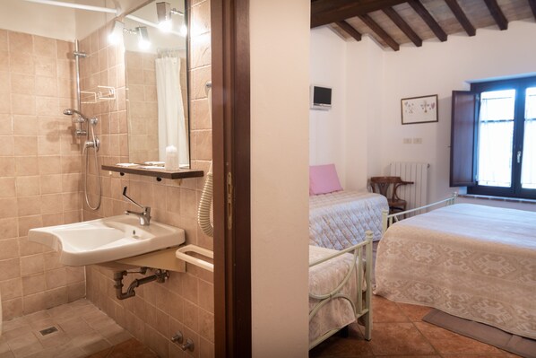 Un baño con lavamanos, ducha y cama con ventana.