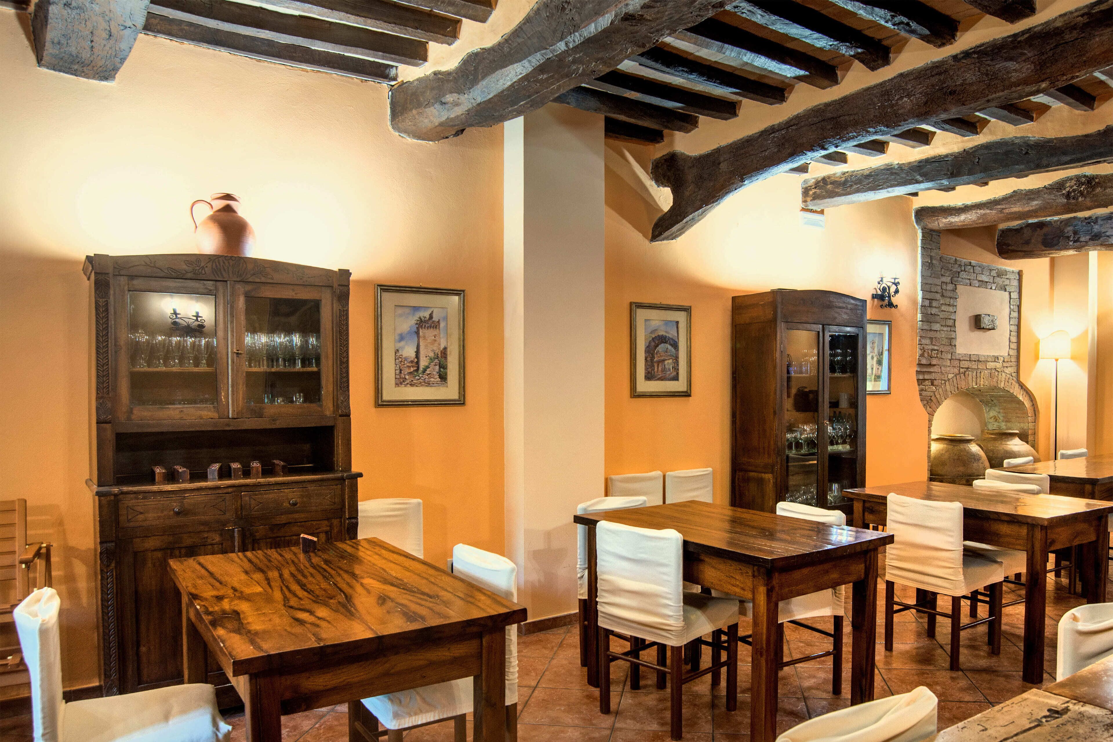 A dining area with wooden tables and chairs, a cabinet with glass doors, and a stone fireplace.