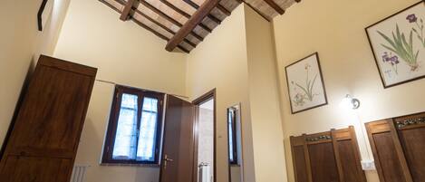 A bedroom with a wooden ceiling, a bed, a window, a radiator, and a mirror.